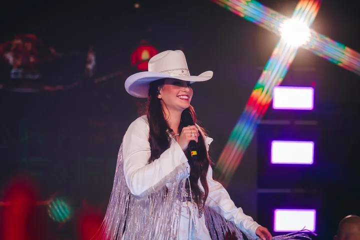 Clara Faria de chapéu branco no palco