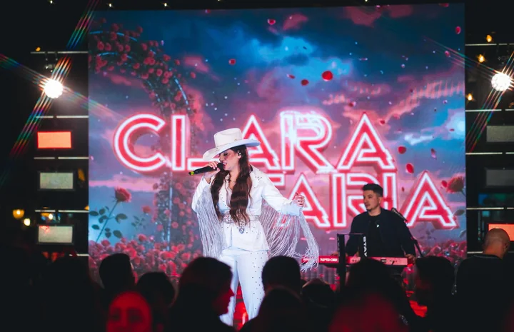 Clara Faria diante do cenário com seu nome